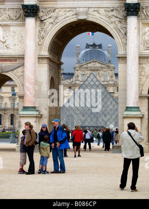 Les touristes au musée du Louvre avec la célèbre pyramide visible à travers une arche dans le palace Paris France la verticale Banque D'Images