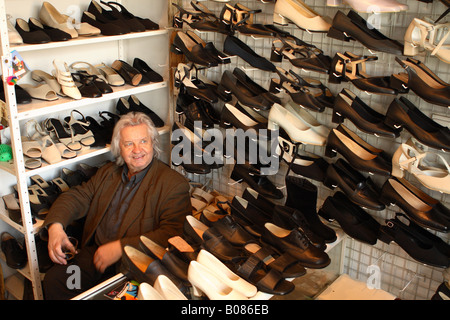 Varsovie Pologne polonaise un petit commerçant dans le quartier Praga derrière son comptoir avec son stock de chaussures fabriquées localement Banque D'Images