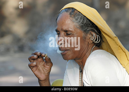 Vieille femme tribale fumant du bidi, une cigarette artisanale indienne faite de tabac ou de feuilles de beedi. La tribu de Bhil. Visages ruraux de l'Inde Banque D'Images