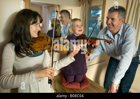 Une mère et sa petite fille pratique le violon comme un fier père regarde sur Banque D'Images