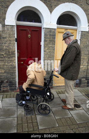 Vieux monsieur avec sa femme en fauteuil roulant à l'extérieur de la maison Banque D'Images