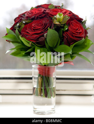 Bouquet de roses rouges en face de la fenêtre. Banque D'Images