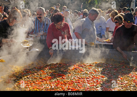 Foule rassemblée autour d'une immense Paella de tva au cours de la fiesta, Altea la Vella, Alicante, Costa Blanca, Espagne Banque D'Images