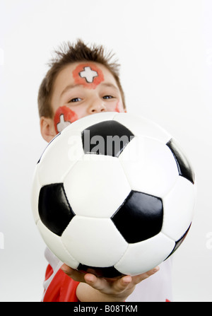 Garçon, rouged que Swiss fan de foot, avec le football dans sa main et d'un drapeau Banque D'Images