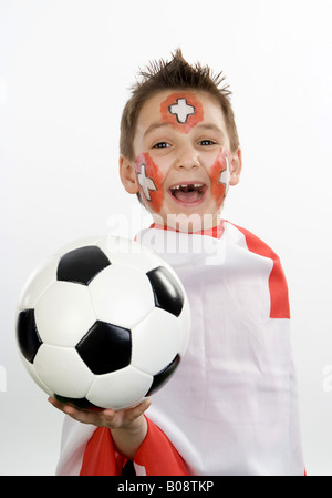 Garçon, rouged que Swiss fan de foot, avec le football dans sa main et d'un drapeau Banque D'Images