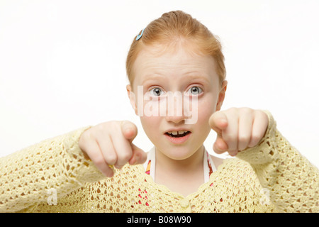 Rousse de 8 ans portant un chandail en tricot jaune, cavalier, pointant sur l'appareil photo Banque D'Images