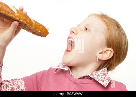 8-year-old girl with red hair mordre dans une baguette Banque D'Images