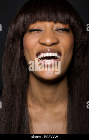 Portrait d'une jeune femme à la peau sombre rire Banque D'Images