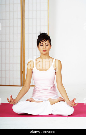 Jeune femme assise en position du lotus, méditant Banque D'Images