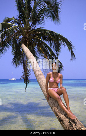 Caraïbes belle femme assise sur un Palm à la mer, le Belize, la mer des Caraïbes, Ranguama Cay Banque D'Images