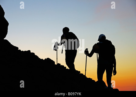 Deux randonneurs dans twilight se profilant comme ils marchent jusqu'au volcan actif sur l'île de Stromboli, Iles Eoliennes, Italie Banque D'Images