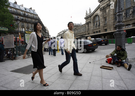 Un mendiant sur le trottoir et les gens qui marchent par, Paris, France Banque D'Images