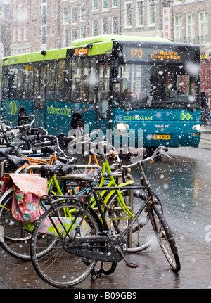 Amsterdam Nieuwezijds Voorburgwal, rue de chute de neige, bus et vélos en stationnement Banque D'Images