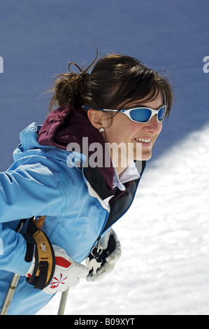 Jeune femme avec des lunettes de soleil et de bâtons de ski, France, Alpes Banque D'Images