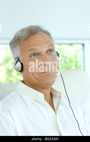 Man listening to headphones, smiling, looking up Banque D'Images