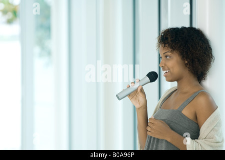 Young woman singing into microphone, looking away Banque D'Images