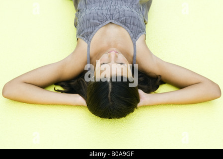 Teenage girl allongé sur le dos avec les mains sous la tête, les yeux fermés, high angle view Banque D'Images