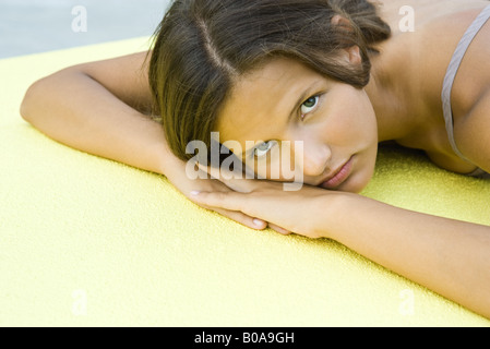 Teenage girl lying on stomach, tête posée sur les bras, looking at camera Banque D'Images