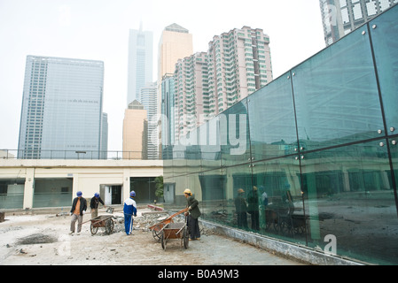 Les hommes avec des brouettes sur site de construction en milieu urbain Banque D'Images