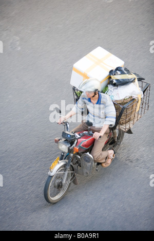 Man riding moped chargé avec les boîtes, high angle view Banque D'Images