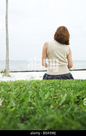 Femme assise sur le sol, face à la mer, vue arrière Banque D'Images