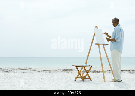 Man peinture sur toile à la plage, vue latérale Banque D'Images