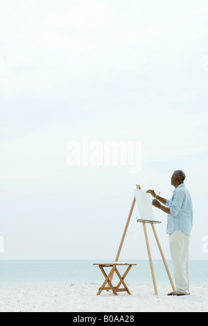 Man peinture sur toile à la plage, vue latérale Banque D'Images