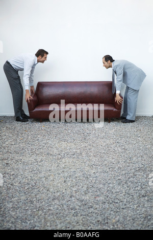Deux businessmen standing décrochant canapé, regarder, side view Banque D'Images