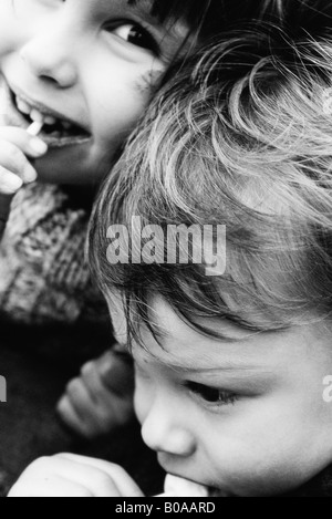 Deux frères et sœurs manger lollipops, girl smiling, portrait Banque D'Images