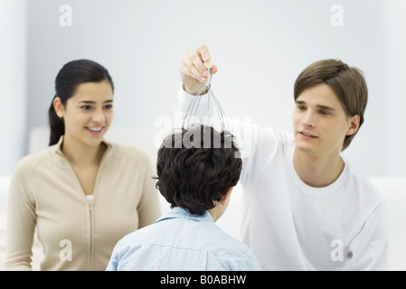 Jeune homme et femme avec boy, essayer masseur de tête Banque D'Images