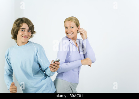 Mère et fils adolescents listening to MP3 player ensemble, danser, smiling at camera Banque D'Images