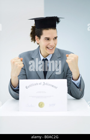 Jeune homme, vêtu avec diplôme graduation cap, at work Banque D'Images