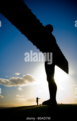 Silhouette de silhouette debout avec les bras étirés au pied de l'Ange du Nord à Gateshead. Vu contre un ciel bleu Banque D'Images