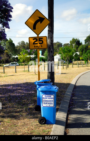 Panneau de circulation et wheelie bin, avec 'Veuillez ralentir, examiner nos kids' imprimé sur ben. Banque D'Images