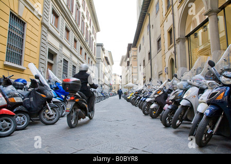 Un coureur au centre de Florence, dans une rue pleine de garé motor cycles Banque D'Images