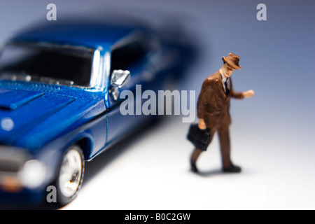Porte-documents avec figurine homme debout à côté d'une voiture bleue Banque D'Images