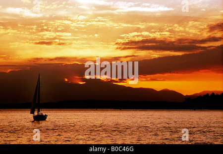 Un voilier navigue dans le coucher de soleil sur Seattle's Elliot Bay. Banque D'Images