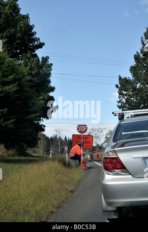 L'homme assis à travaux routiers avec panneau d'arrêt Banque D'Images