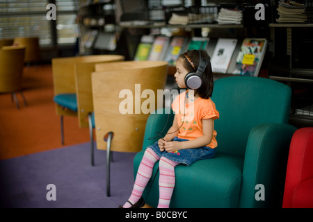 Bibliothèque centrale Palmerston North Nouvelle Zélande quatre ans, fille, à l'écoute des émissions de radio à l'aide d'écouteurs Banque D'Images