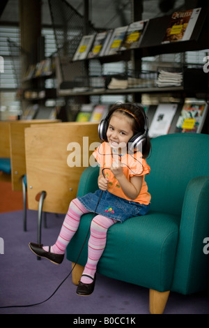 Bibliothèque centrale Palmerston North Nouvelle Zélande quatre ans, fille, à l'écoute des émissions de radio à l'aide d'écouteurs Banque D'Images