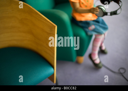 Bibliothèque centrale Palmerston North Nouvelle Zélande quatre ans, fille, à l'écoute des émissions de radio à l'aide d'écouteurs Banque D'Images