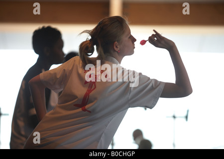 Chers jeunes joueur Zoe Jones se penche en avant pour avant de lancer son tournoi au cours dart flighted rose Banque D'Images