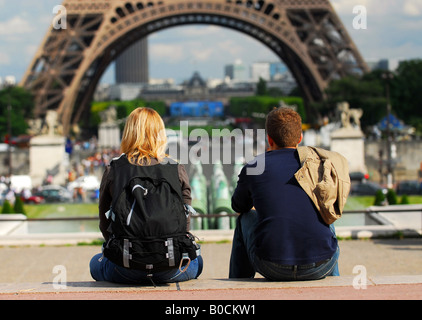 Young tourist couple assis en face de la tour Eiffel à Paris, France Banque D'Images