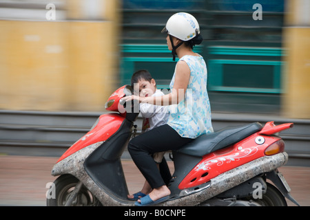 Femme et un garçon fatigué sur un scooter sur Trang Tien, Hanoi, Vietnam Banque D'Images