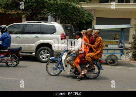 Un homme et trois moines sur la même moto à Phnom Penh, Cambodge Banque D'Images