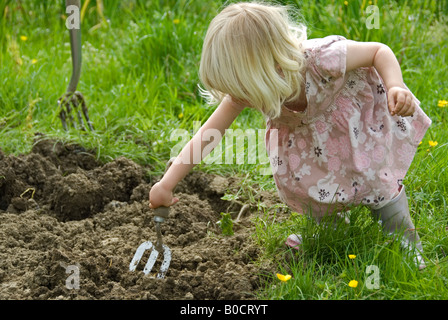 Stock photo d'un petit blond haired fillette de deux ans l'aide au jardinage Banque D'Images