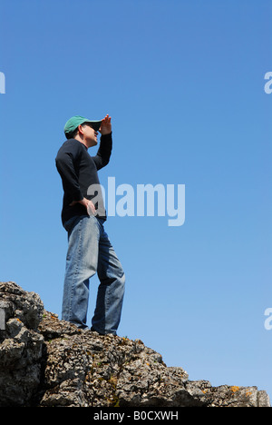 Un homme debout sur le haut d'une falaise à la recherche dans la distance Banque D'Images