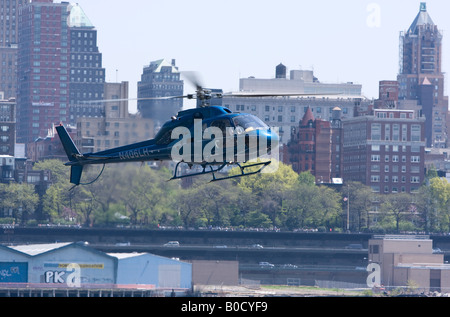 Un hélicoptère s'abaisse sur l'East River dans son approche de la Manhattan Heliport Banque D'Images