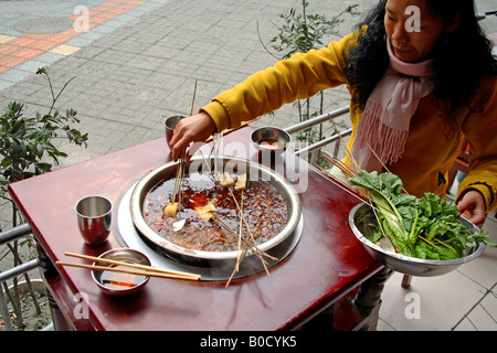 Chinese girl eating traditionell Sichuan food Banque D'Images