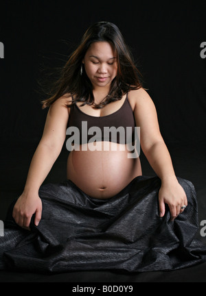 Young pregnant Asian woman sitting cross-legged dans une pose méditative à ventre vers le bas Banque D'Images